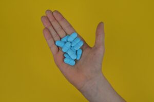 A person holding a handful of blue pills.