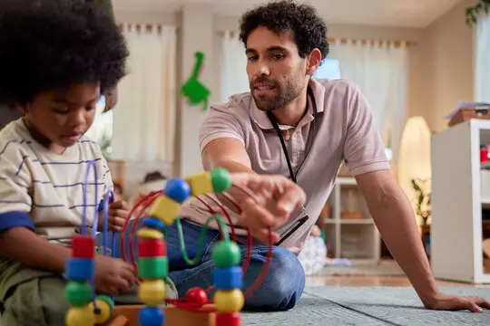 Daycare worker showing toy to toddler Daycare worker showing toy to toddler