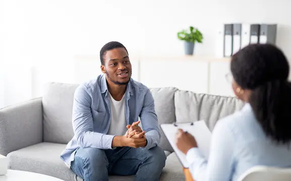 Effective psychotherapy. Young black guy talking to his psychologist, receiving professional help at mental health clinic Effective psychotherapy. Young black guy talking to his psychologist, receiving professional help at mental health clinic